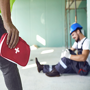 Injured construction worker with knee pain, receiving a first aid kit.