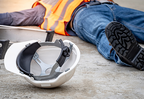 Construction worker lying injured on the ground with a safety helmet nearby, symbolizing lost wages and future earning potential due to injury